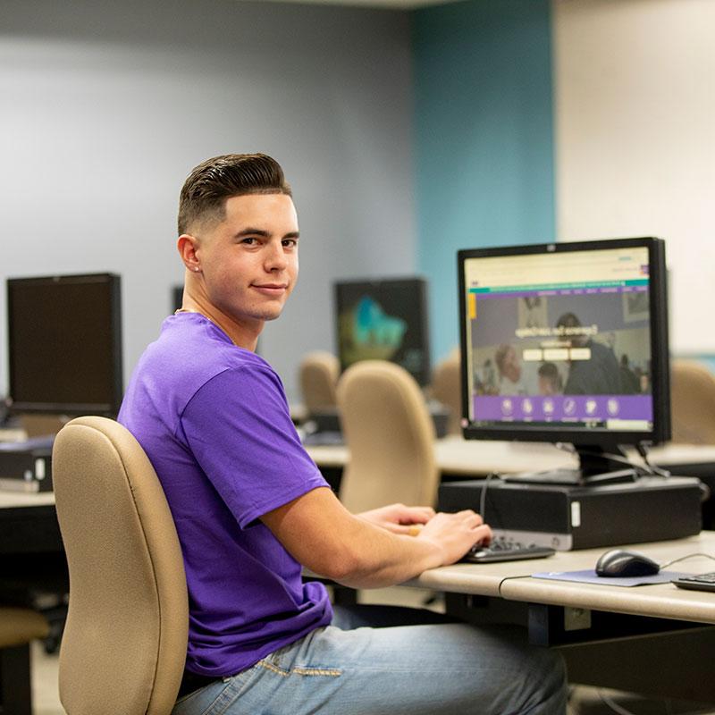 Student sitting at the computer in his IT class.